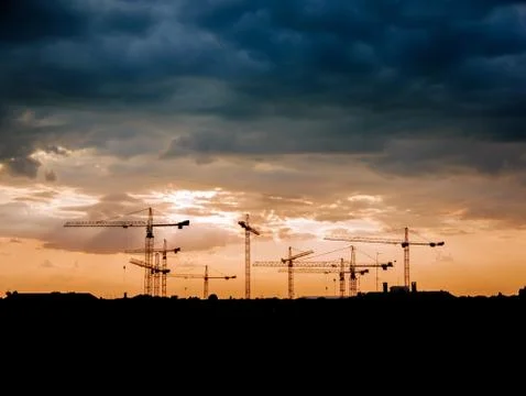 View on a consturction site with cranes during sunset Stock Photos