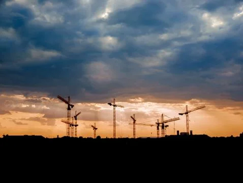 View on a consturction site with cranes during sunset Stock Photos