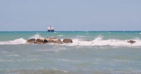 View of a container ship from the Bari seafront with the rough sea breaking t Vídeo Stock 152582777