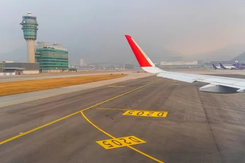 View of the control tower and passenger terminal with an airplane wing view.  Stock Photos