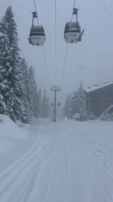 View of Courchevel ski resort slopes with ski lifts on a snowing day by winter Vídeo Stock 334427024