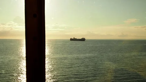 View from a cruise ship on a cargo ship in the sea and the bright sun reflection Stock Footage 248529716