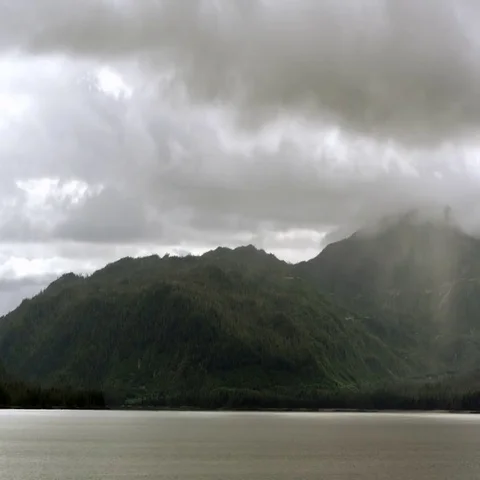 View from a cruise ship moving through the water parallel with a mountain Stock Footage 69658449