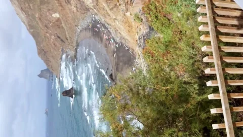 View of a cup of coffee in a viewpoint towards a paradisiacal black sand 스톡 동영상 247695314
