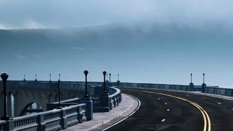 View of curved road with lamp posts near coastline under cloudy sky Stock Footage 340628027