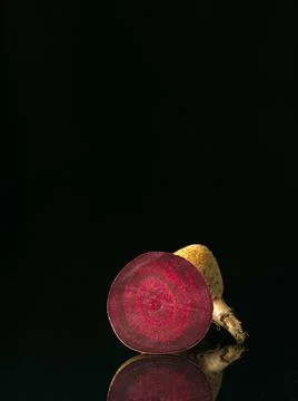 View to the cut raw beetroot. Black background with reflection. Two part of beet Stock Photos
