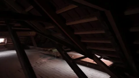 View of dark attic space with dormer window illuminating the floor. Old, shabby Stock Footage 311447991