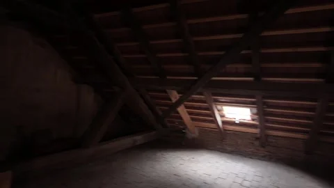 A view of dark attic space lit by a light bulb. An old, shabby house intended Stock Footage 311059665