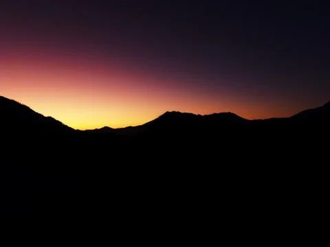 View of the dark outlines of a mountain range against the backdrop of an Stock Photos