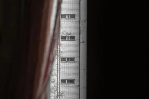 A view from a dark window on a vertical row of narrow windows in a modernist  Stock Photos