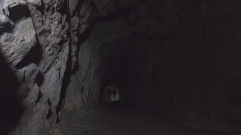 View deep cave with figures of two people with lanterns Stock Photos
