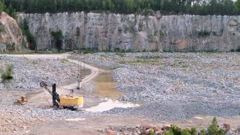 View of a deep granite quarry with granite mining equipment. Tall stone cliff Video stock 134493492