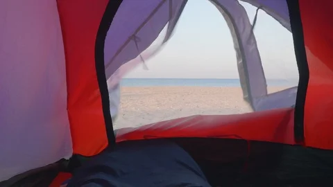 View of deserted beach and blue sea through little window in tent Stock Footage 95940824