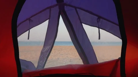 View of deserted beach and blue sea through little window in tent Stock Footage 95940850