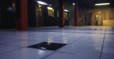 View of a dimly lit underground station floor with tiles and drain cover Stock Illustration