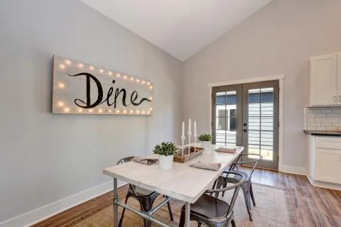 View of dining table with wooden top and metal chairs. French doors lead out  Stock Photos