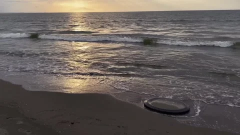 View of a discarded car tire bathing on a beach at sunset in Dagupan city. Video stock 260947110
