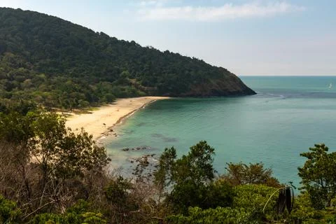 A view of a distant beach surrounded by lush forest on the island of Koh Lant Stock Photos