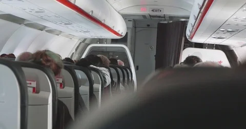 View down the aisle from behind the seat of passengers sitting in their seats Stock-Footage 107454765