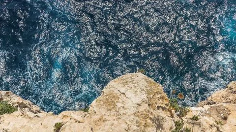 A view down from a cliff to the ocean. Stock Photos