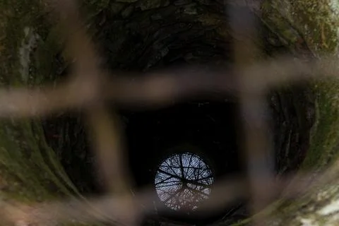 View Down an Old Stone Well with Metal Grid and Moss Covered Walls Stock-Fotos