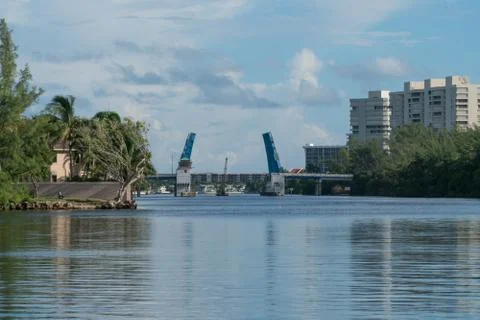 View down river to open drawbridge in distance allowing tall boat to pass Stock Photos