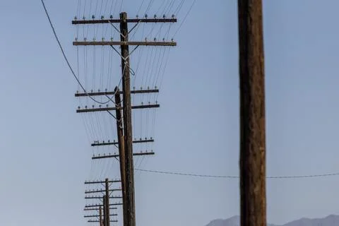 View down a row of utility poles against sky background Stockfoto's