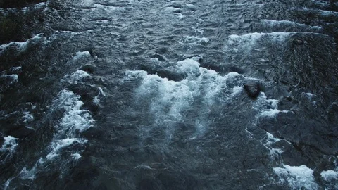 A view down towards a river, with water rushing by rocks Vídeos de archivo 118189357