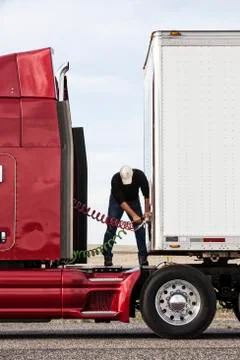 View of a driver connectiing the power cables to trailer of a  commercial truck. Stock Photos