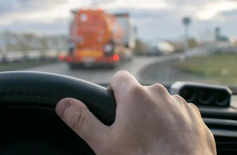 View of the driver hand on the background of a fuel truck driving in front Stock Photos