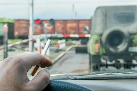 View of the driver hand with a cigarette on the steering wheel of the car Stock Photos