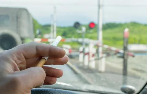 View of the driver hand with a cigarette on the steering wheel of the car Stock Photos