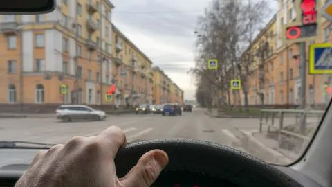 View of the driver hand inside the car, waiting for the traffic light Stock Photos