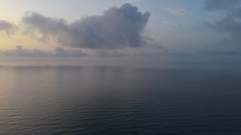 View from drone above sea surface at dawn with sun highlighting clouds and .. Stock Footage 314273023