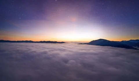 View from the drone at dawn over the clouds with mountains on the grassland. Foto stock