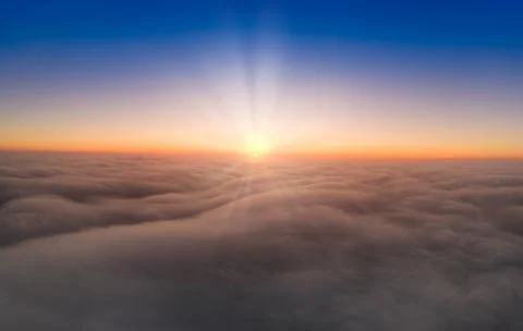 View from the drone at dawn over the clouds with mountains on the grassland. Stock Photos