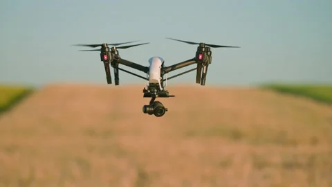 View of drone with digital video camera flying above field in harvest on blurred Stock Footage 213673286
