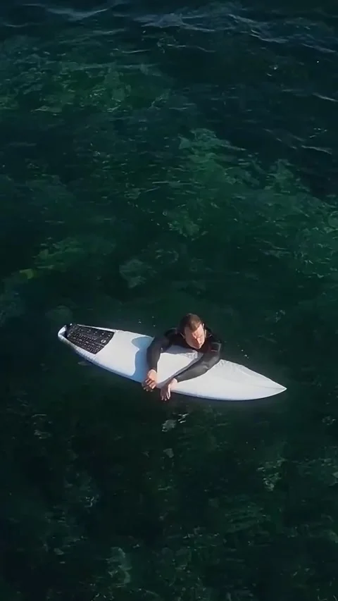 View from drone at man with his surfboard waits a wave in the sea Stock Footage 321049752
