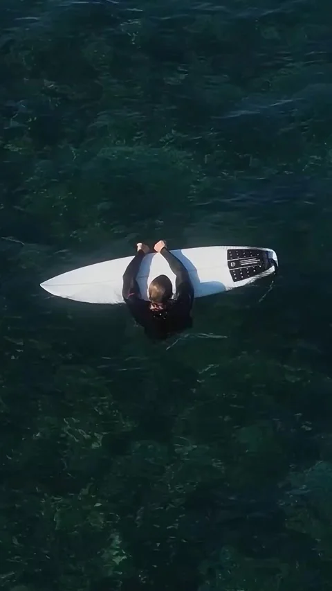 View from drone at man with his surfboard waits a wave in the sea Stock Footage 321049760