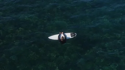 View from drone at man with his surfboard waits a wave in the sea Stock Footage 321049844