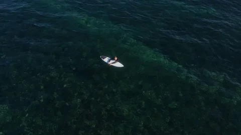 View from drone at man with his surfboard waits a wave in the sea Stock Footage 321049862