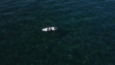 View from drone at man with his surfboard waits a wave in the sea Stock Footage 321049891