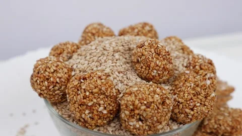 View of dropping sesame ladoo over bowl filled with sesame seeds Stock Footage 147694975