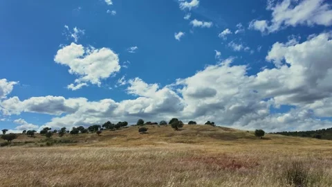 View of a dry field and a hill under a cloudy sky, Portugal. Vidéo 335602064