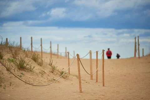 View of dunes protected by wooden posts and ropes with two people out of fo.. Stock Photos