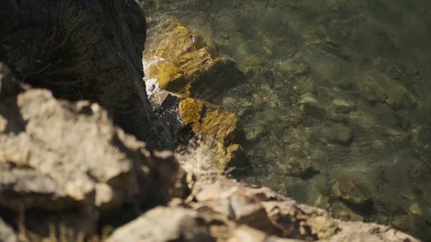 View from edge of cliff on water below, water hits rocks Stock Footage 127405561