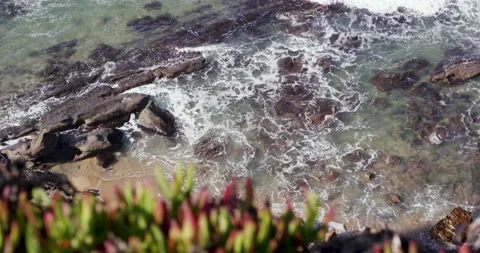 View from edge of rocky cliff on wavy ocean moving and splashing in slow motion Stock Footage 156280342