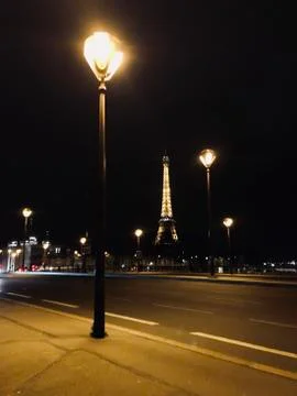 View of Eiffel Tower over road with city lights on, Paris, France Stock Photos