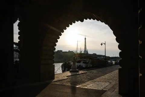 View of the Eiffel Tower through the arch of a Parisian bridge. Stock Photos