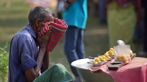 View of an elderly man covering his face by a food stall, Bangladesh. Video stock 335015349